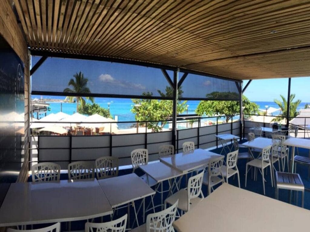 Stores verticaux guidés sur la terrasse d'un restaurant face à la mer