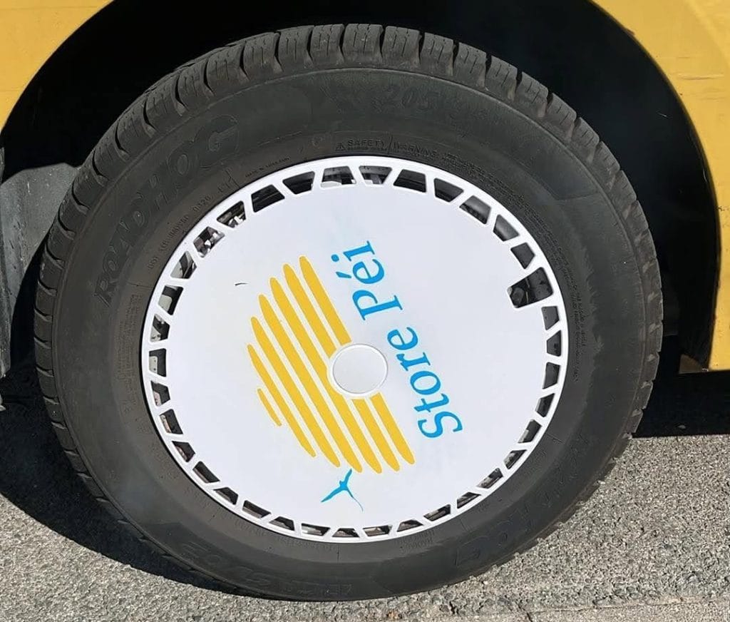 Gros plan sur l'enjoliveur Store Péi installé, logo ruche jaune et paille-en-queue bleu