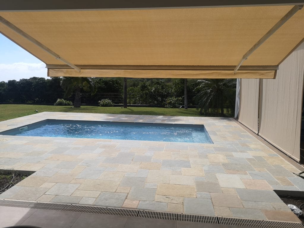 Store banne et store vertical protégeant une terrasse de piscine à La Réunion