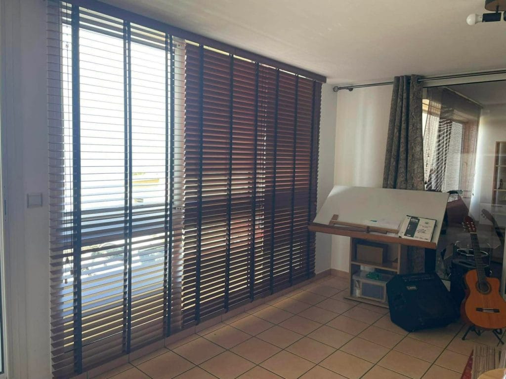 Store vénitien bois, lames entrouvertes pour filtrer la lumière